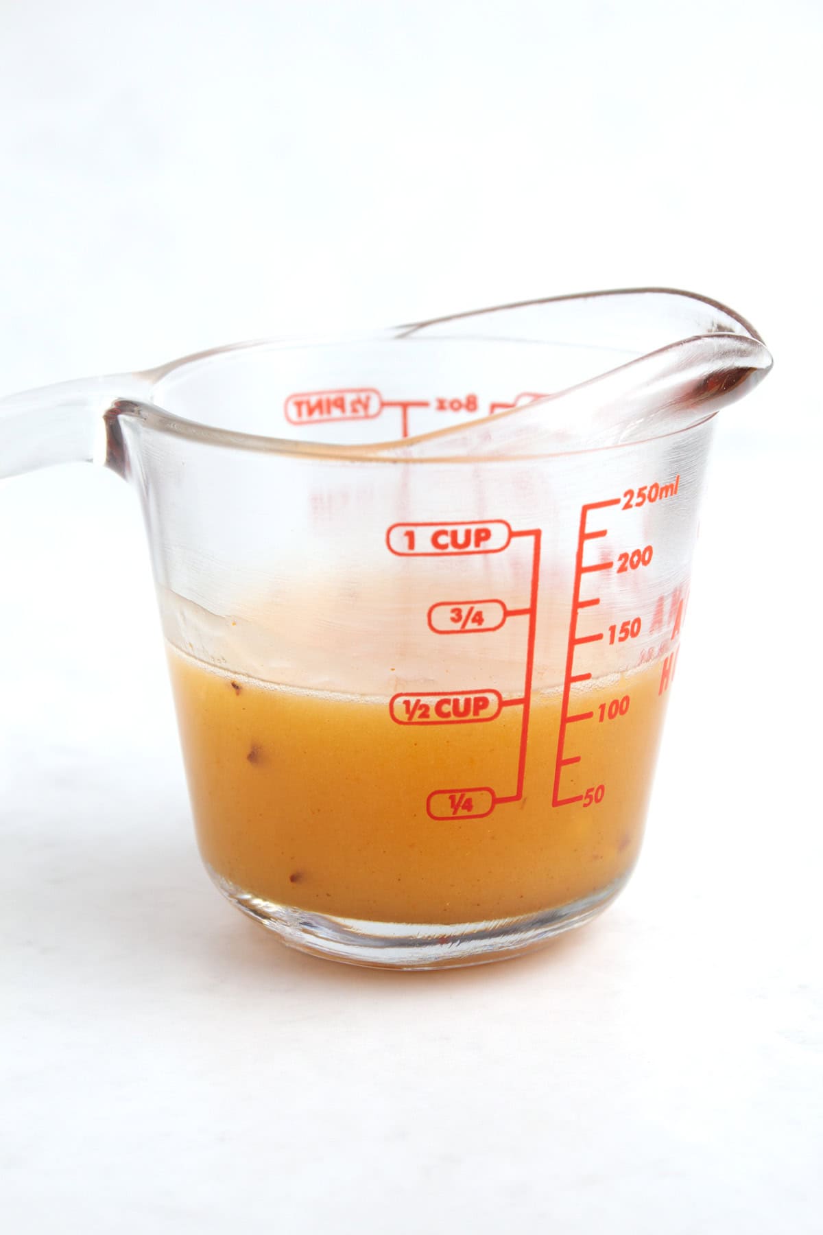 A 1 cup glass measuring container with melted honey, butter, and spices mixed together.