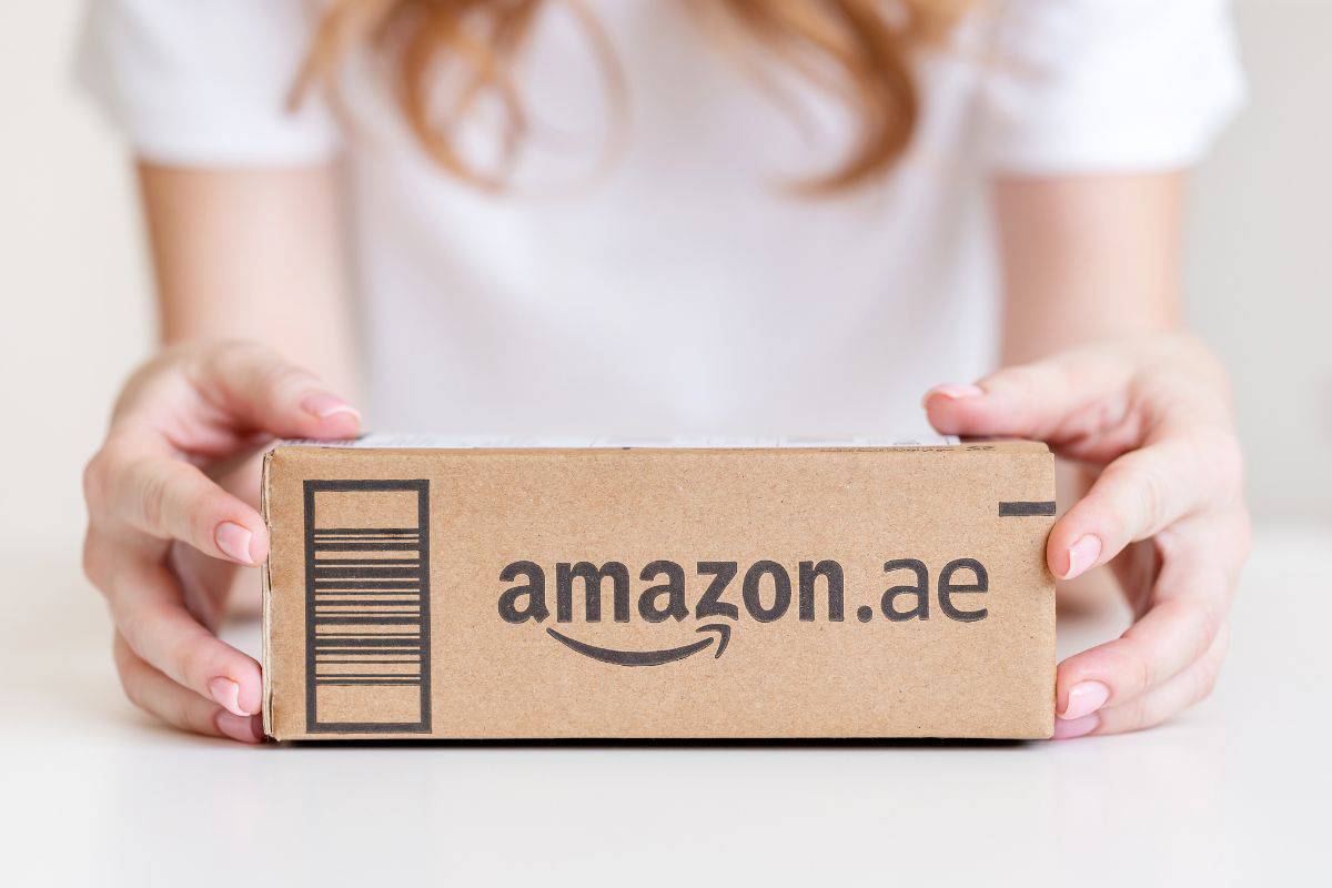 A small Amazon package being held by a person wearing a white shirt.