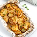 Grilled foil-packet potatoes sprinkled with fresh parsley ready to serve.