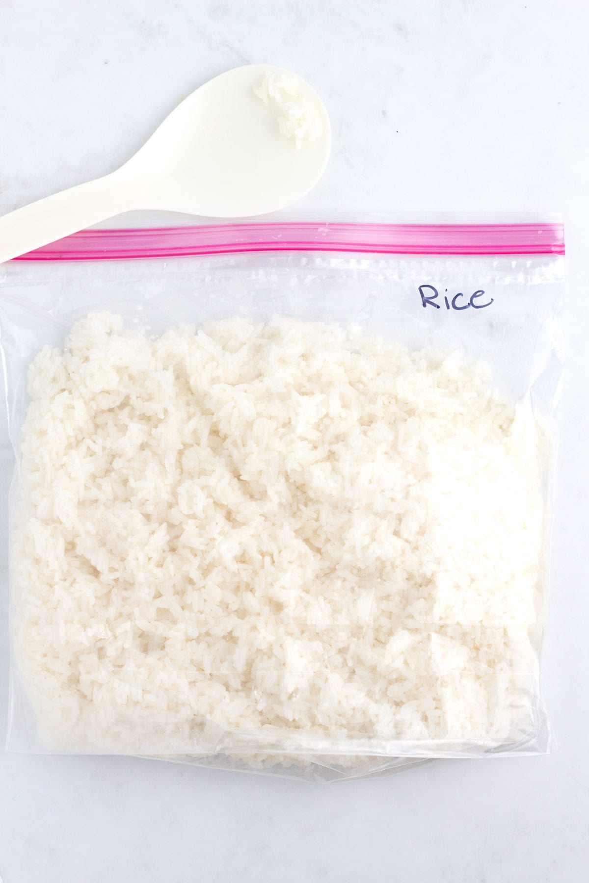 RIce in a freezer bag with a rice paddle laying on the counter.