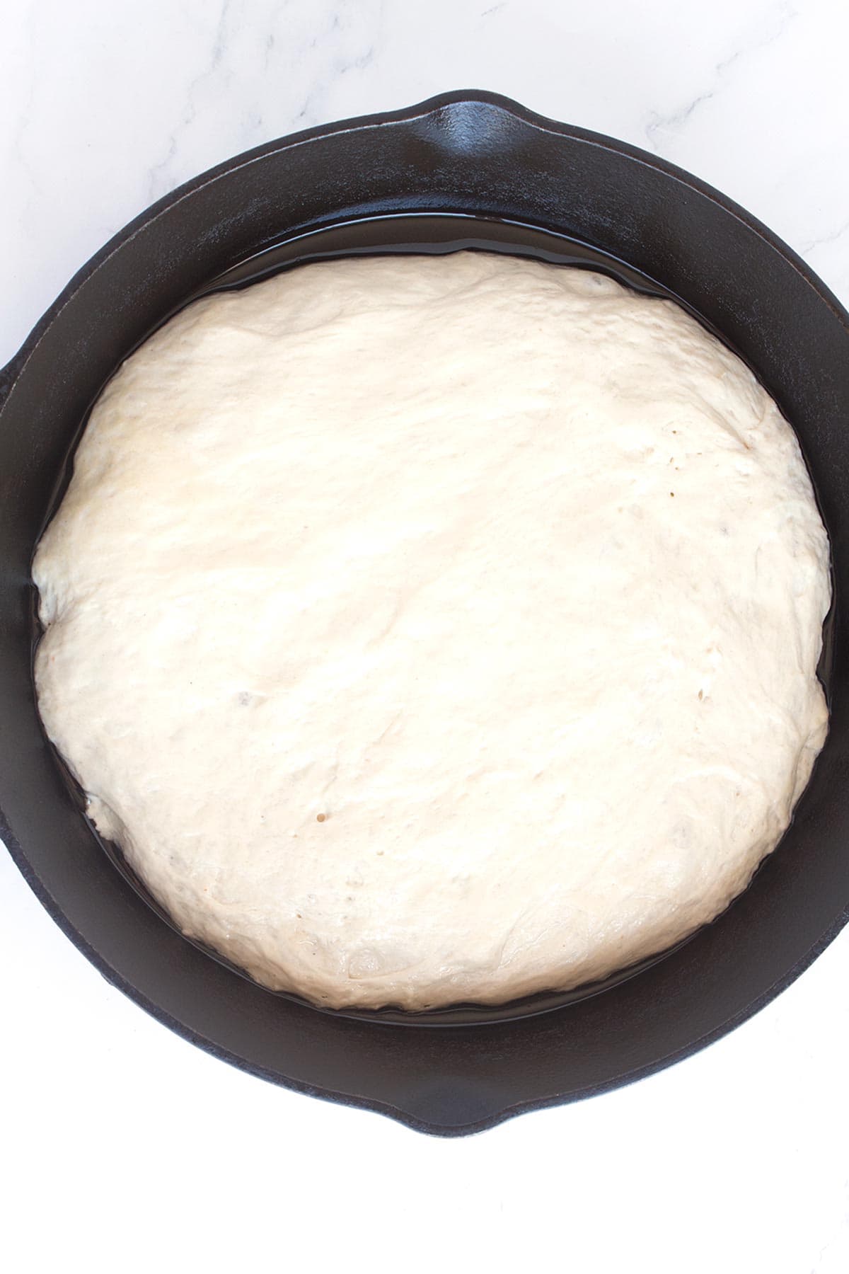 Second step in dough rising in pan before applying pizza toppings.
