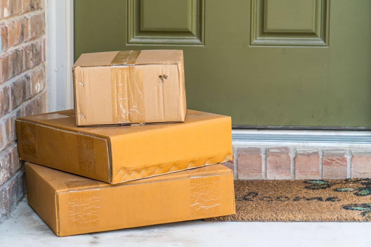 One large, one medium, and one small package stacked on a porch in front of a green door.