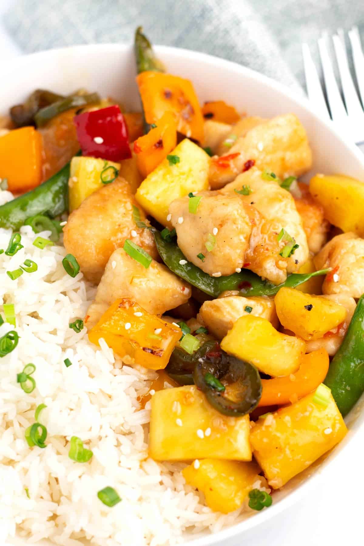 A bowl with white rice on the left and asian stir fry on the right, all sprinkled with green onions.