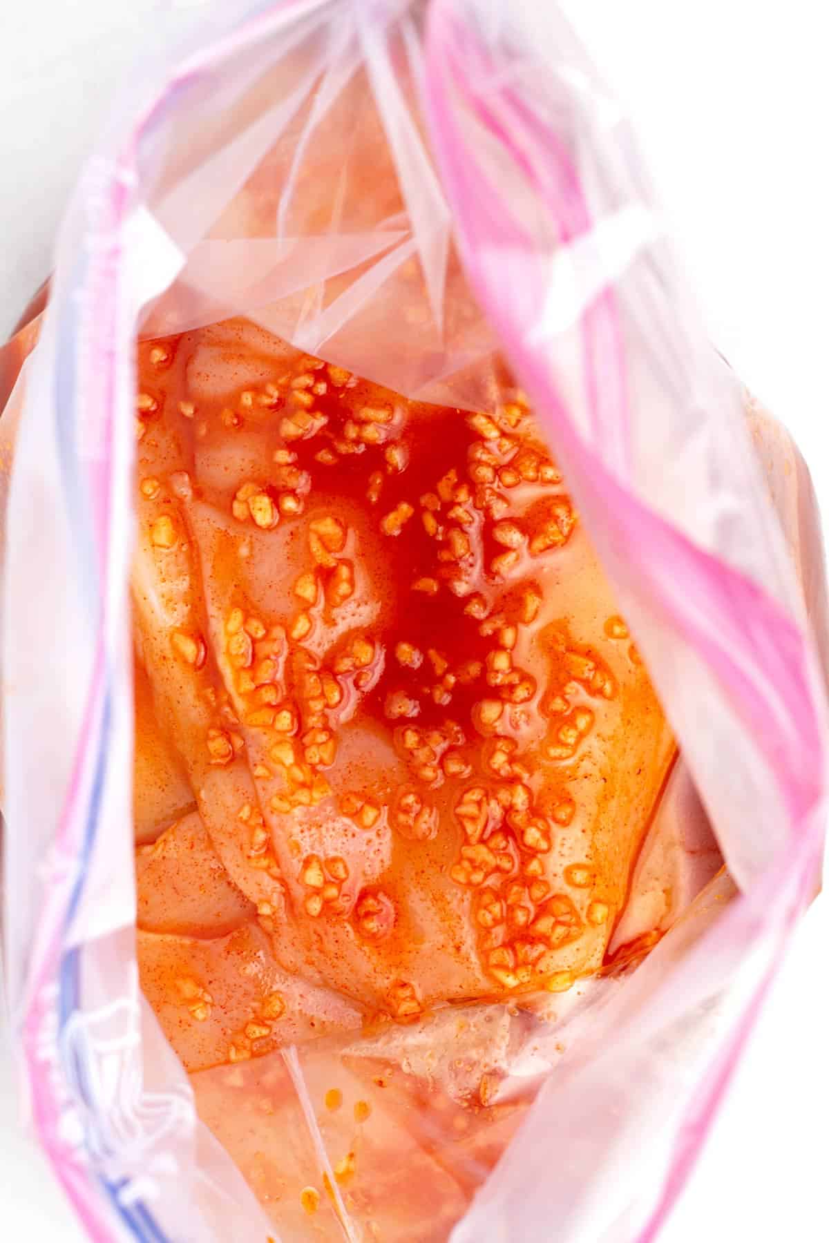 Marinade poured over thinly sliced chicken breasts in zip top bag.