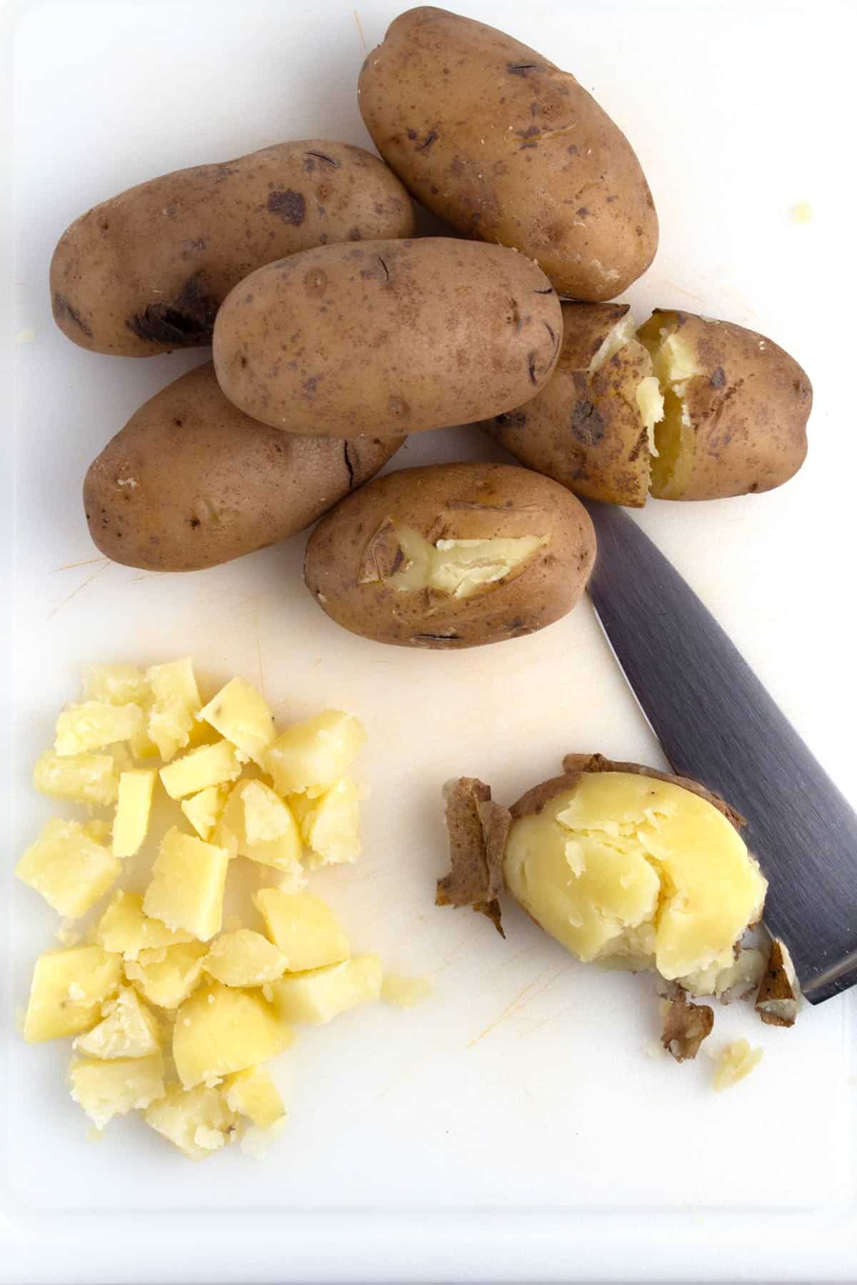 Diced russet potatoes on cutting board after removing jackets.