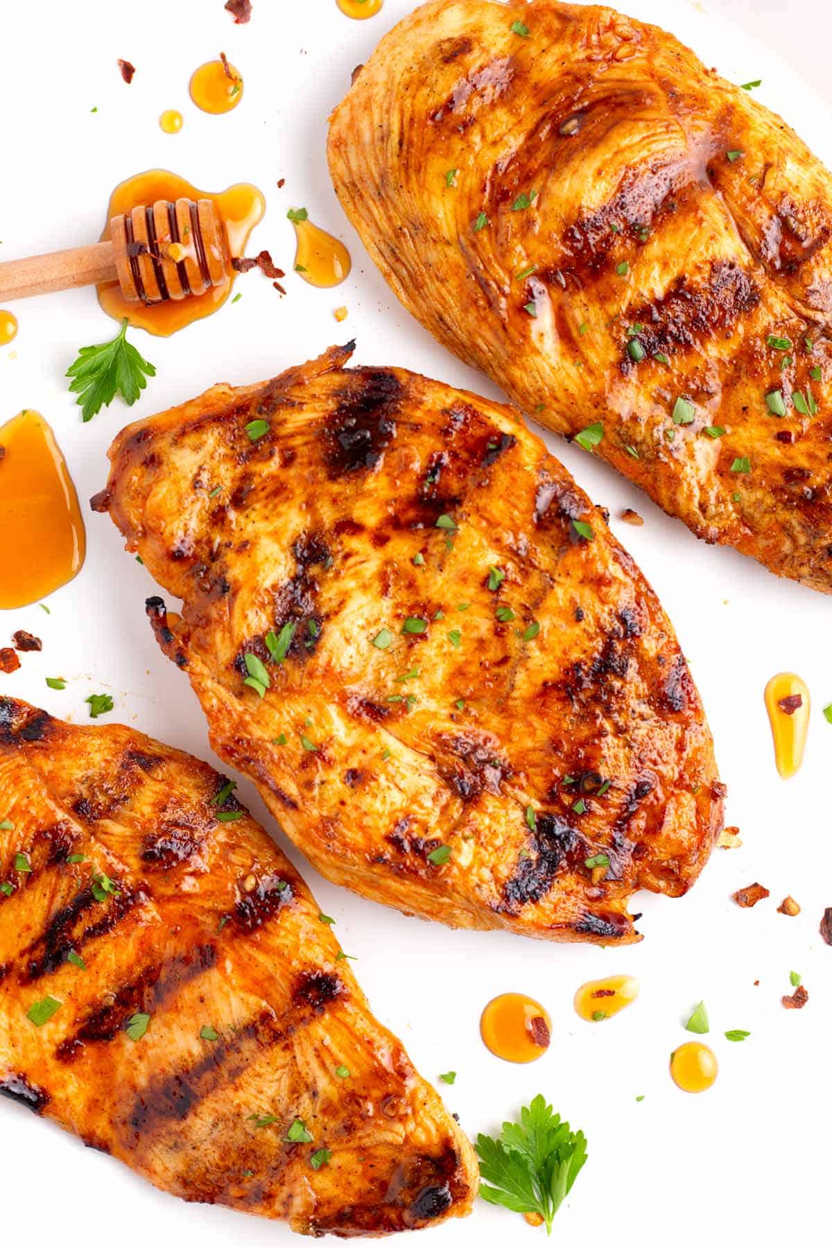 Finished grilled chicken breasts marinated in spicy honey marinade with parsley sprinkled on the top.