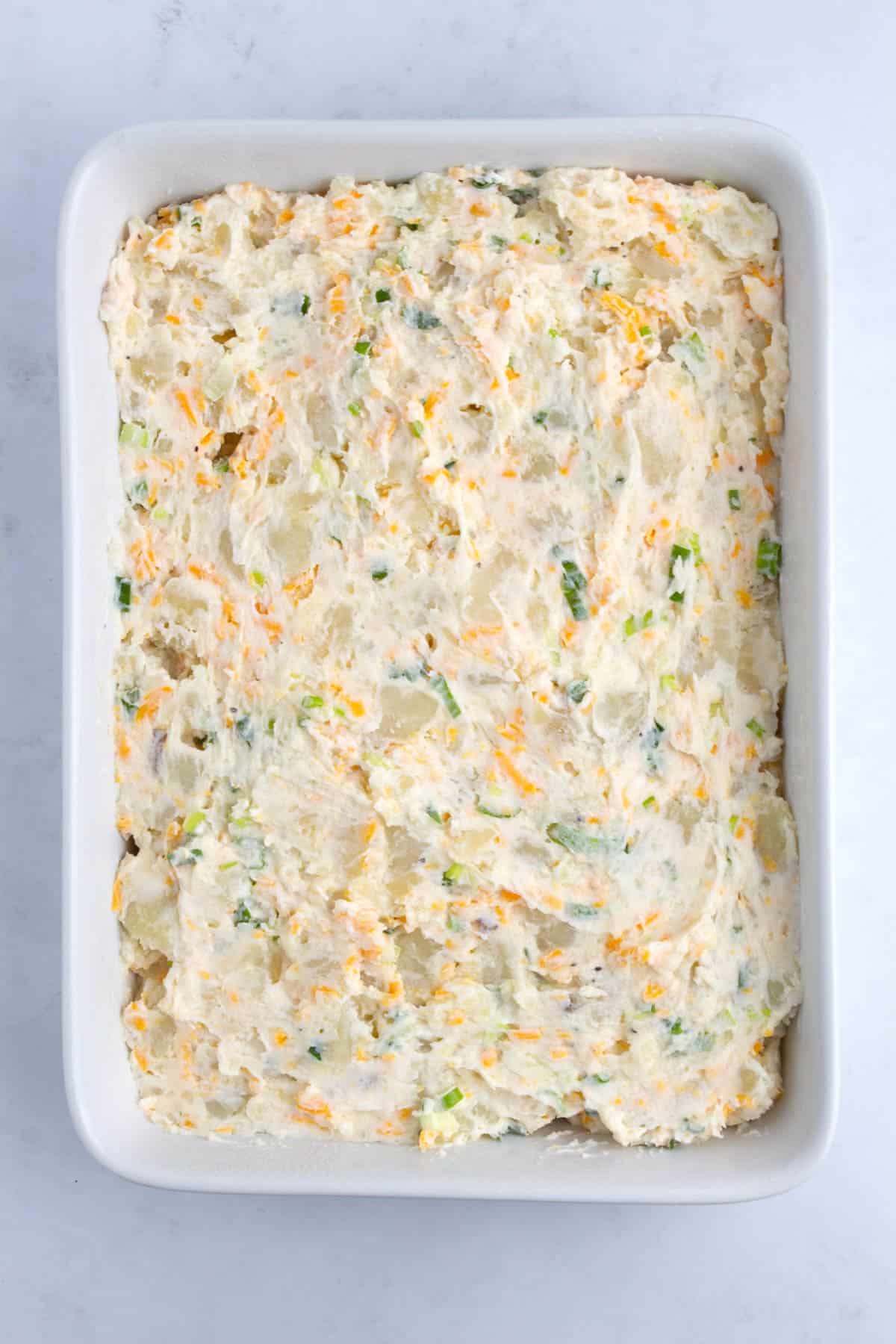 Mixed potato casserole spread out in even layer in casserole dish.