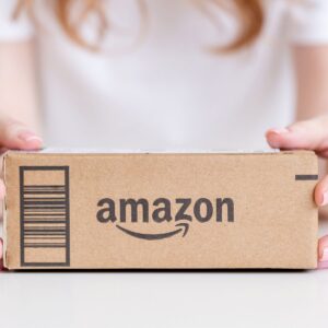 Up close view of a person with her hands on a cardboard box that says Amazon.