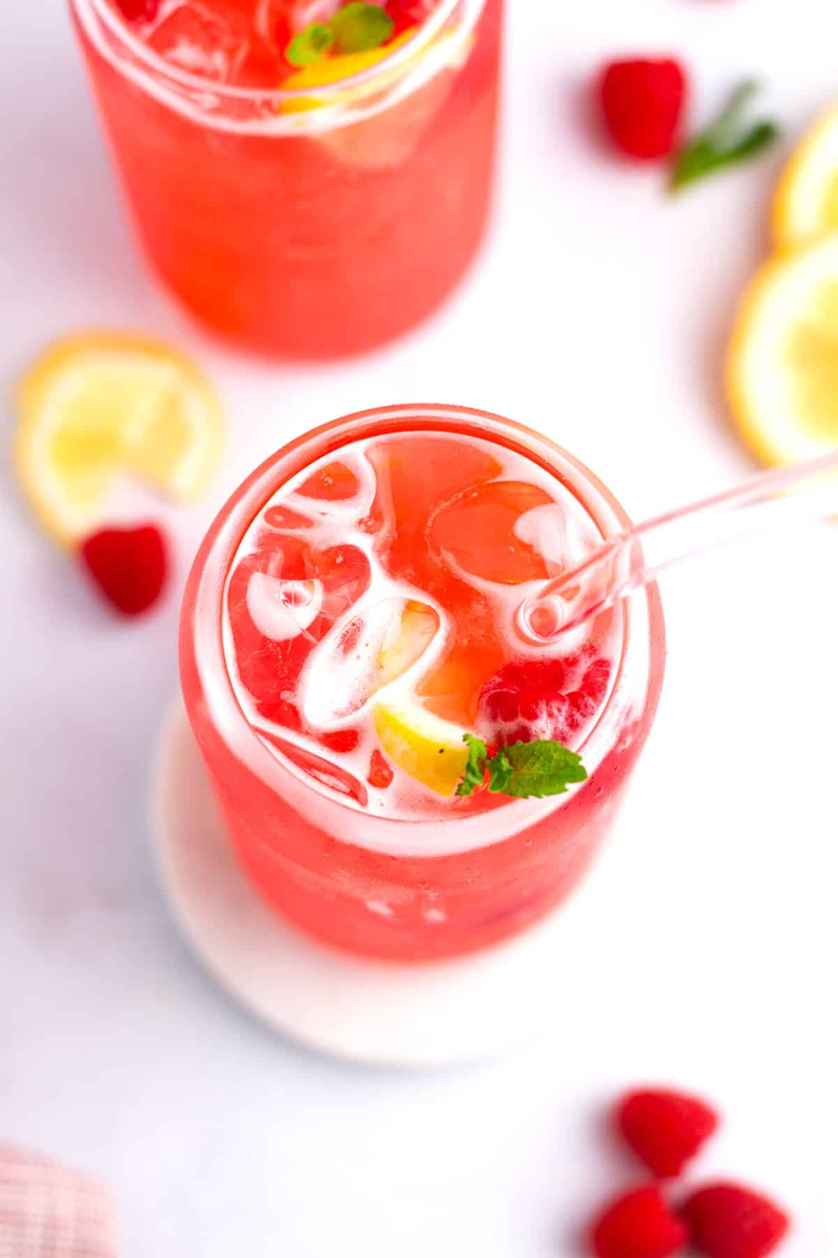 Overhead glass cup with straw in homemade raspberry lemonade.