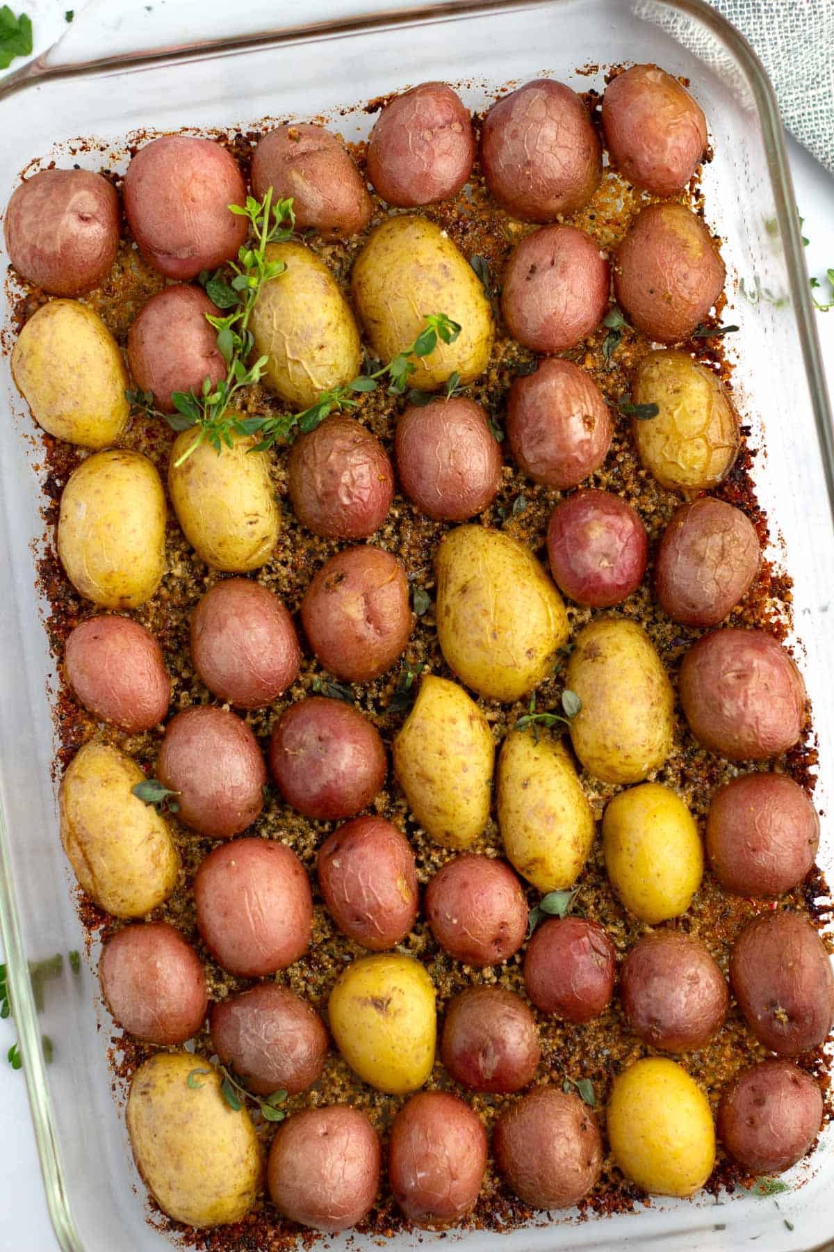 Overhead of baby potatoes with parmesan crust and fresh thyme sprigs.