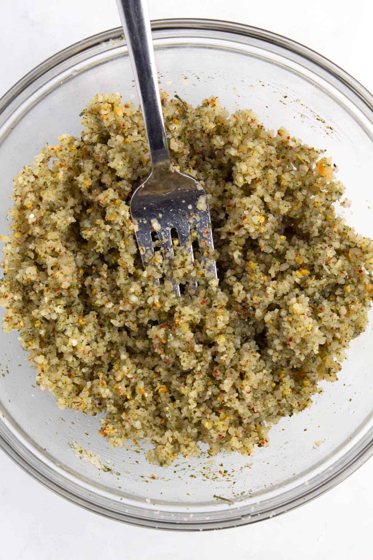 Grated parmesan with seasonings mixed in bowl with fork.