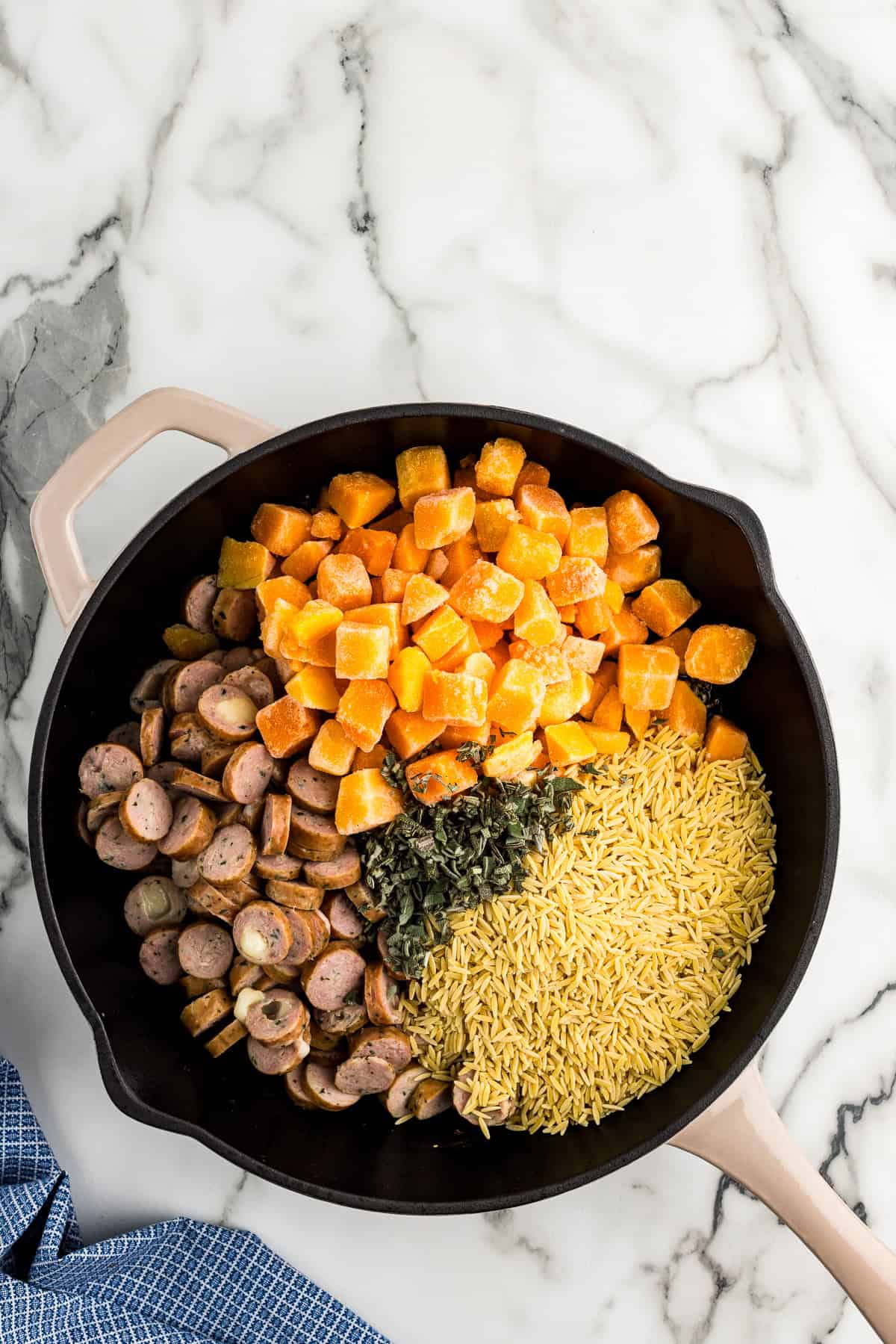 Adding orzo, chicken sausage, butternut squash into skillet.