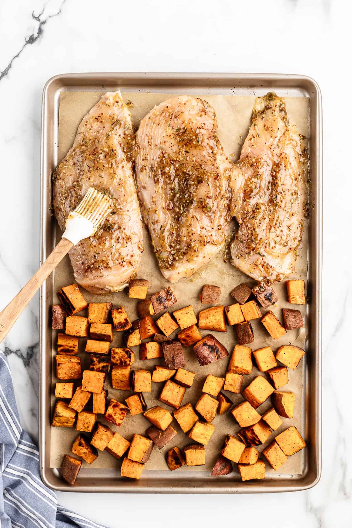 Brushing maple thyme sauce on chicken breasts with silicone brush.