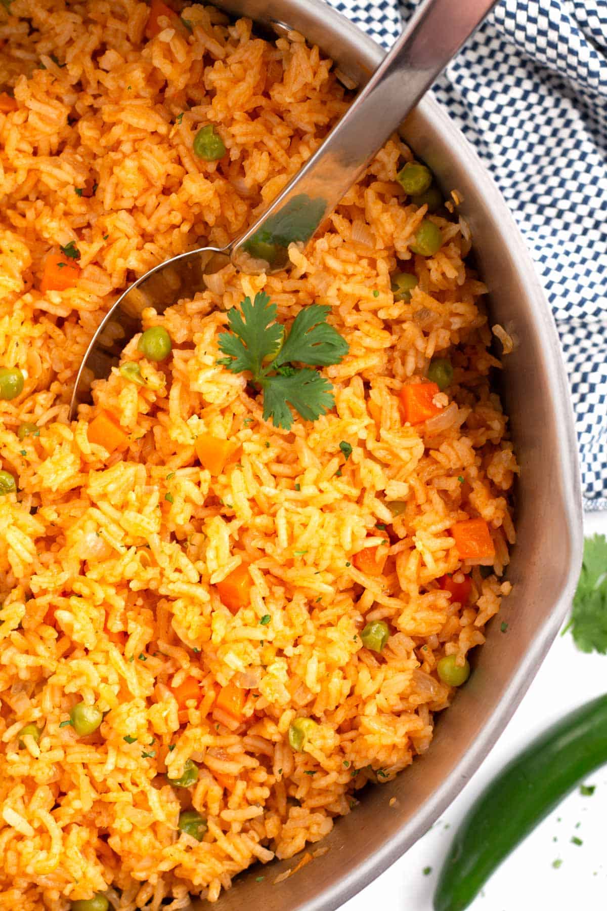 Pot full of prepared Mexican Spanish rice with checkered towel in background.