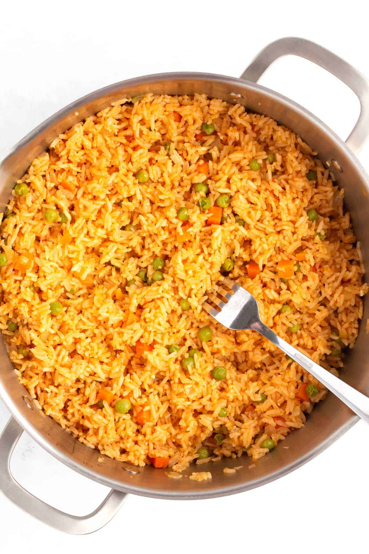 Fluffing Mexican rice with a fork to separate the grains.