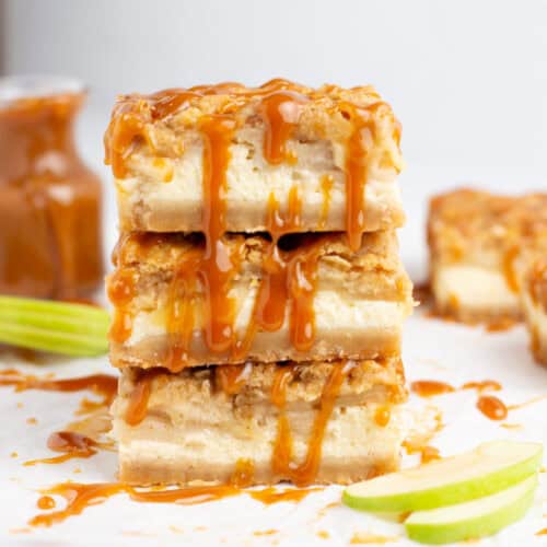 Caramel topping dripping down caramel apple cheesecake bars with thinly sliced apples in the foreground.