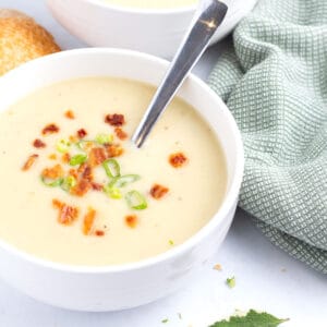 Creamy potato leek soup recipe in a bowl with fresh herbs on top.