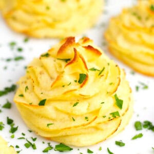 Golden potatoes swirled on a baking sheet with fresh herb garnish.