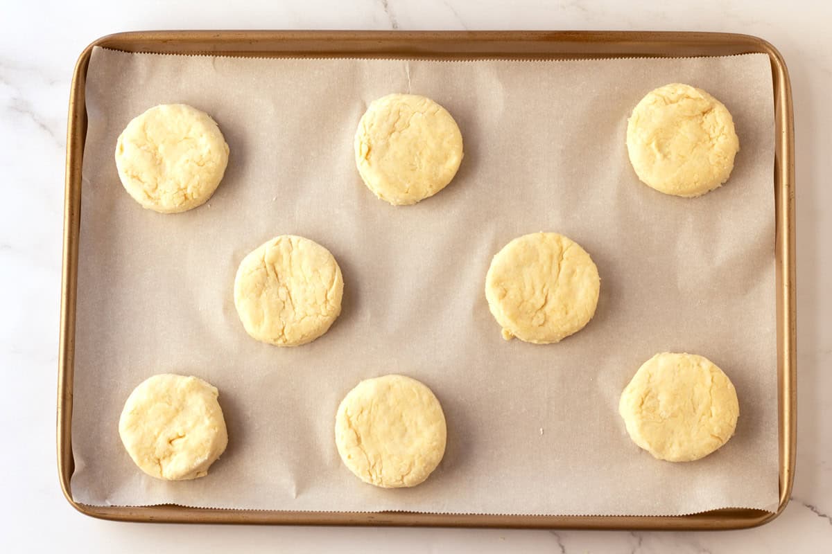 Placing cream biscuits on a sheet pan spacing apart.