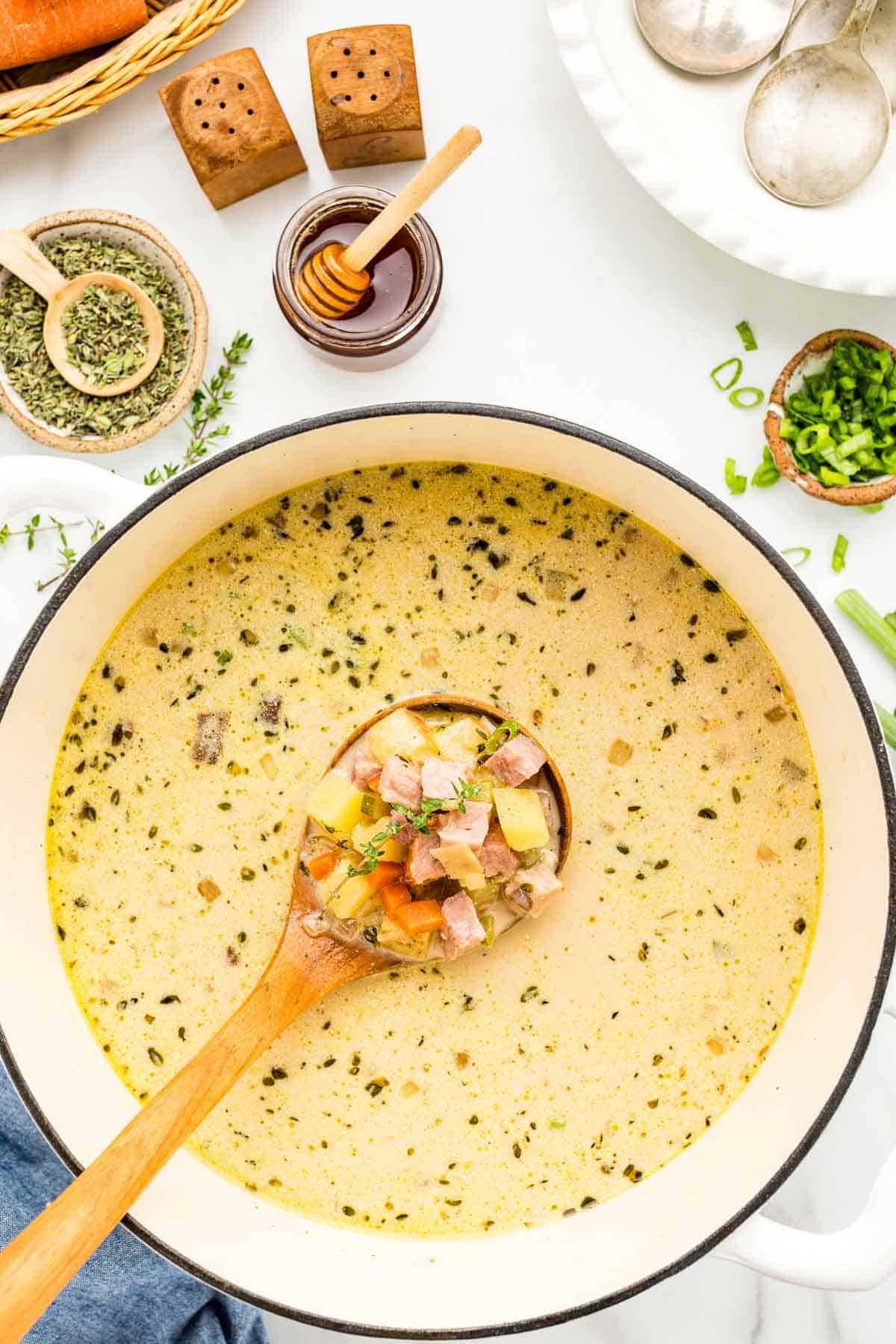 Ladle of ham and potato soup in deeply flavorful broth seasoned with garlic, thyme, honey, and mustard.