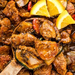 Orange slices on top of pan filled with pork tenderloin stir fry.