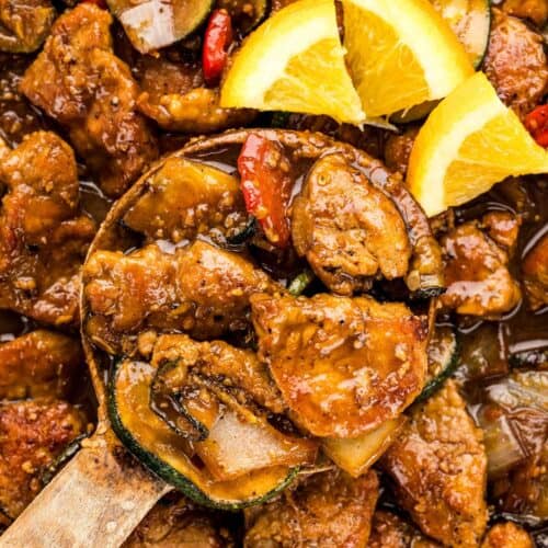 Orange slices on top of pan filled with pork tenderloin stir fry.