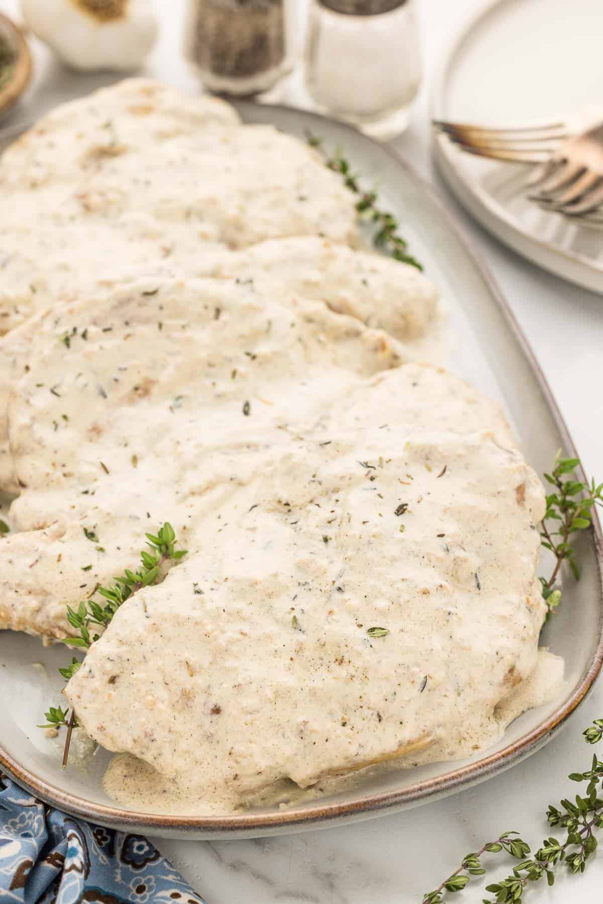 Platter of skillet chicken covered with creamy garlic sauce seasoned with thyme.