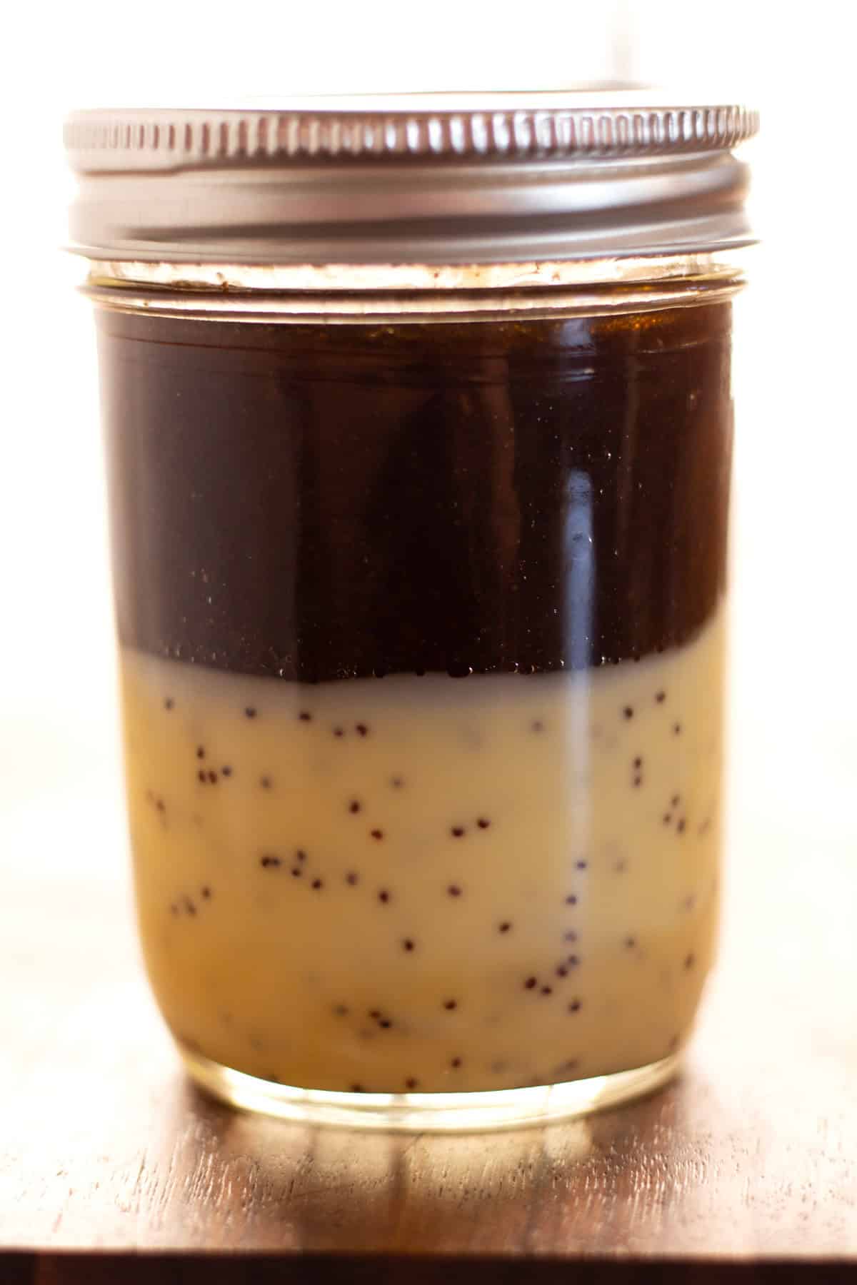 Adding ingredients for dressing in a small jar before mixing.