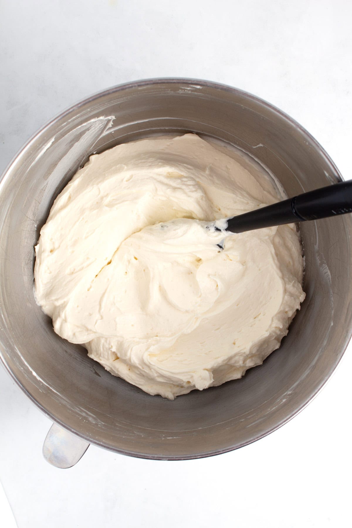 Gently folding whipped cream into cream cheese mixture for no-bake cheesecake.