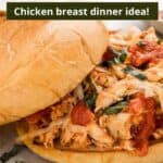 Shredded chicken parmesan sandwich with the top bun sliding off on a piece of parchment paper with green text overlaid at the top of the image.