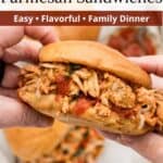 A pair of hands holding a shredded chicken parmesan sandwich over a table with two more sandwiches and a bowl of sauce with red text overlaid at the top of the image.