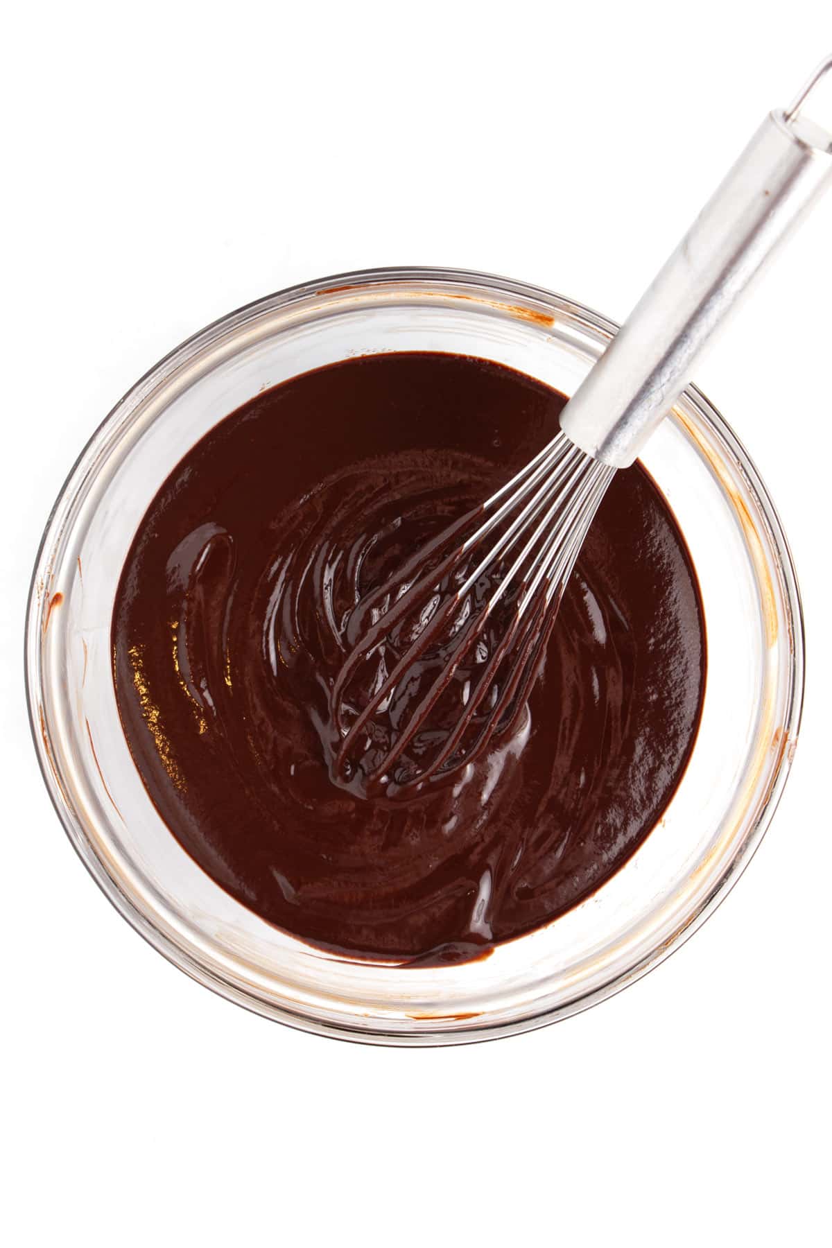Chocolate batter in a glass bowl with a whisk sitting in the bowl.