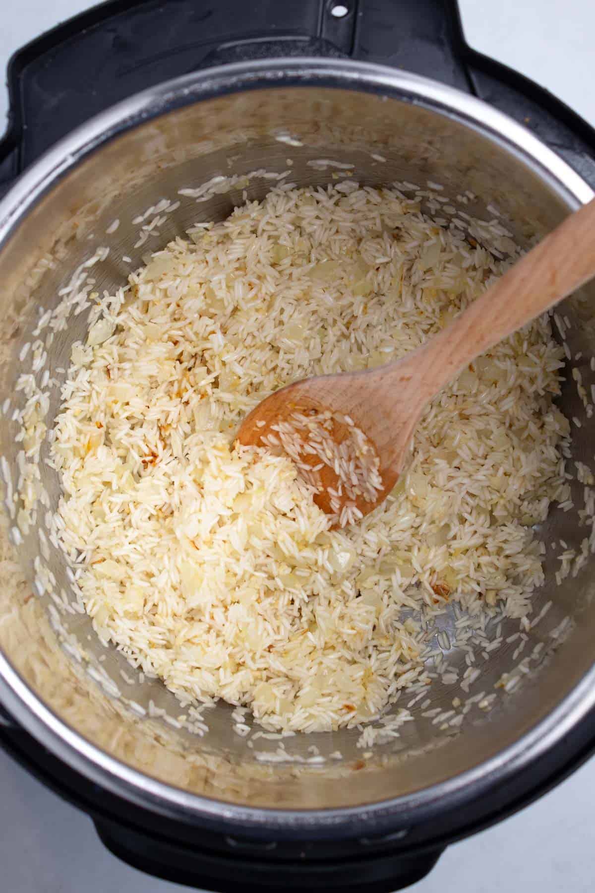 Cooking rice in a large pot with a wooden spoon.