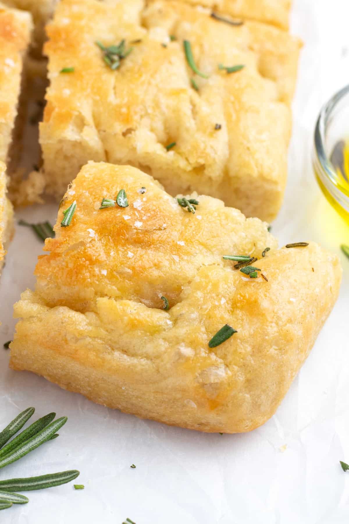 A corner piece from a loaf of focaccia next to the rest of the bread.