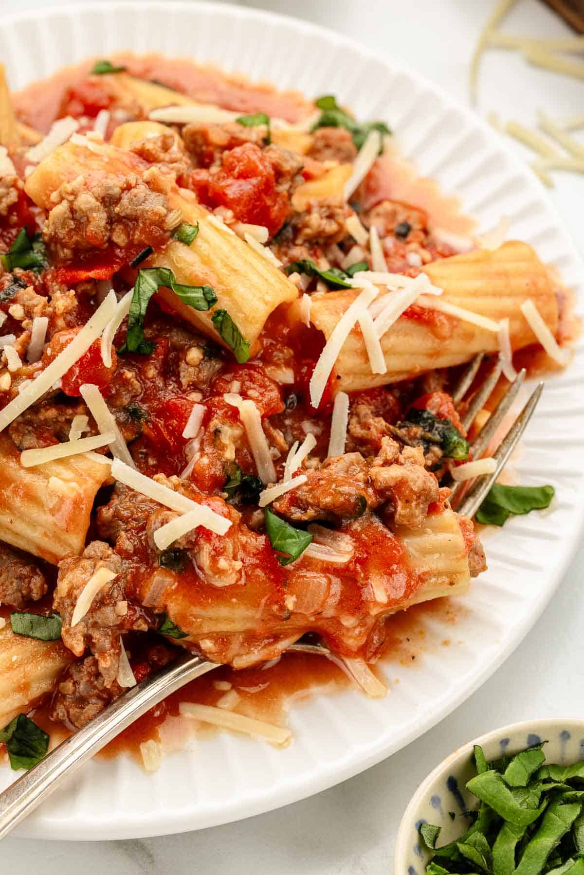 A plate of pasta dinner with sausage with a fork.