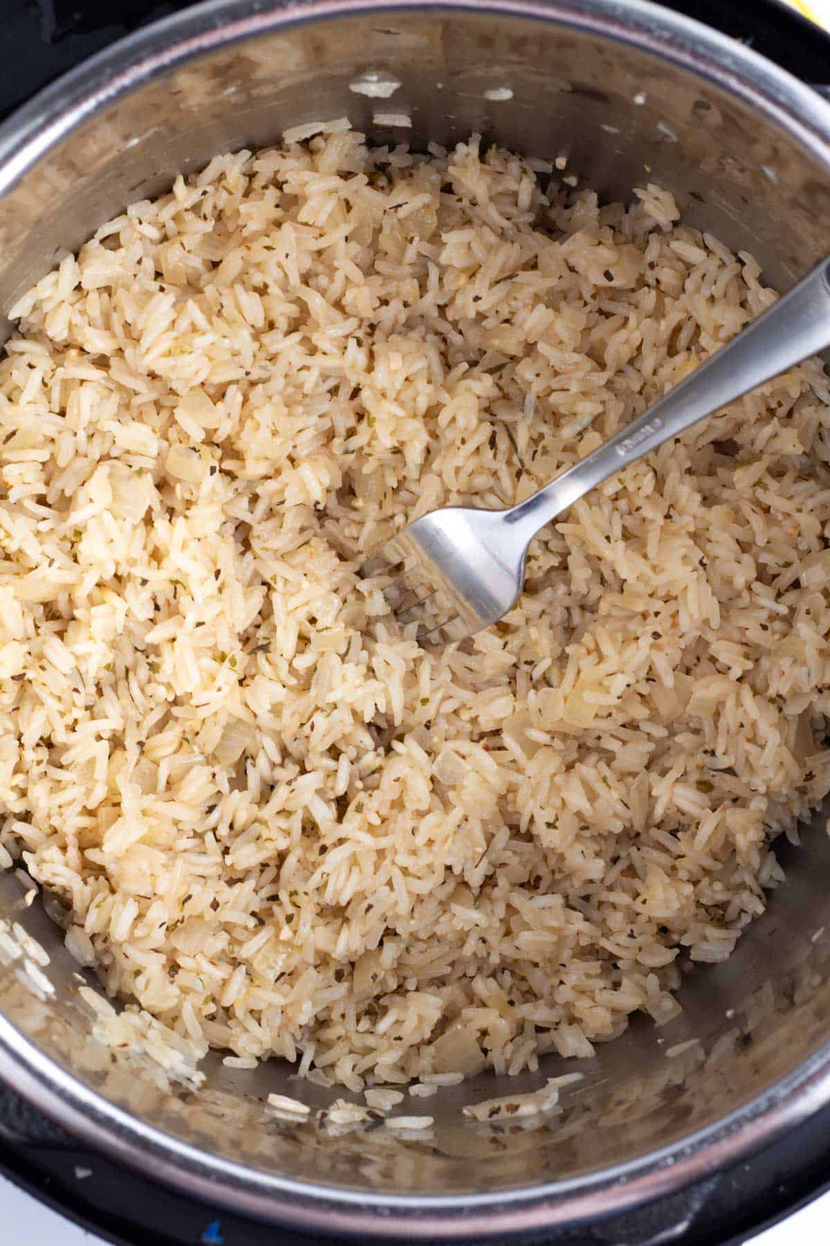 A pot of cooked rice with a fork stuck into it.