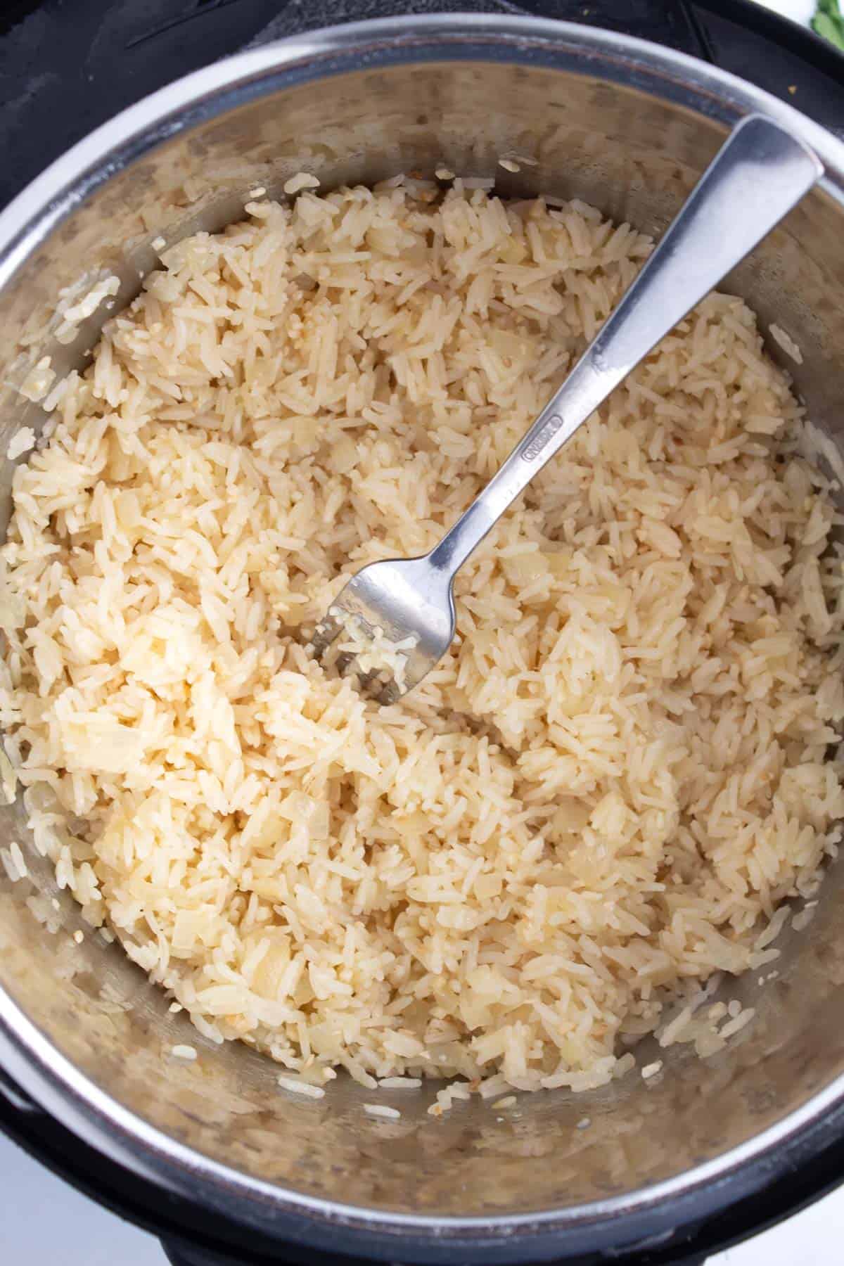 Large pot of cooked rice with a fork sticking out of the center.