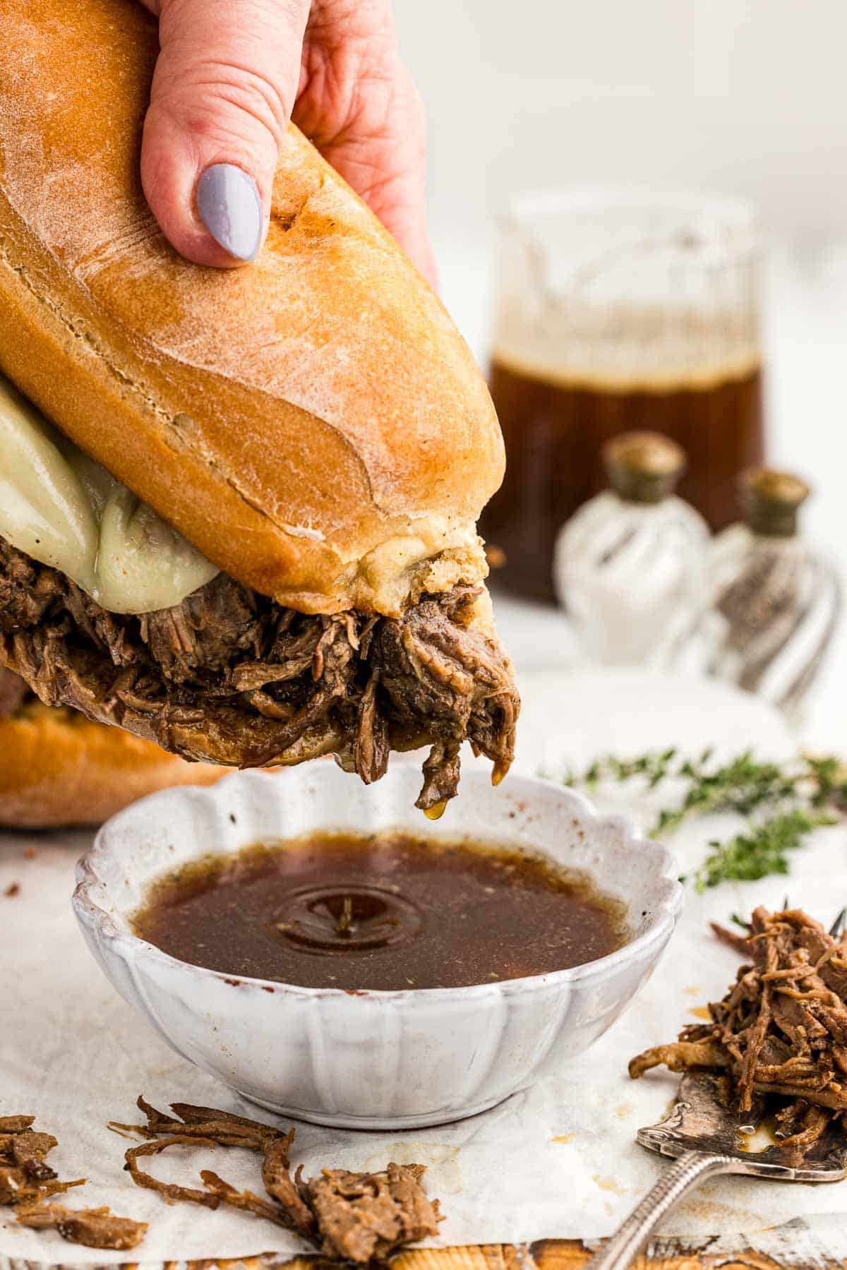 Chuck Roast sandwich dripping with juices over a small bowl of French dip.