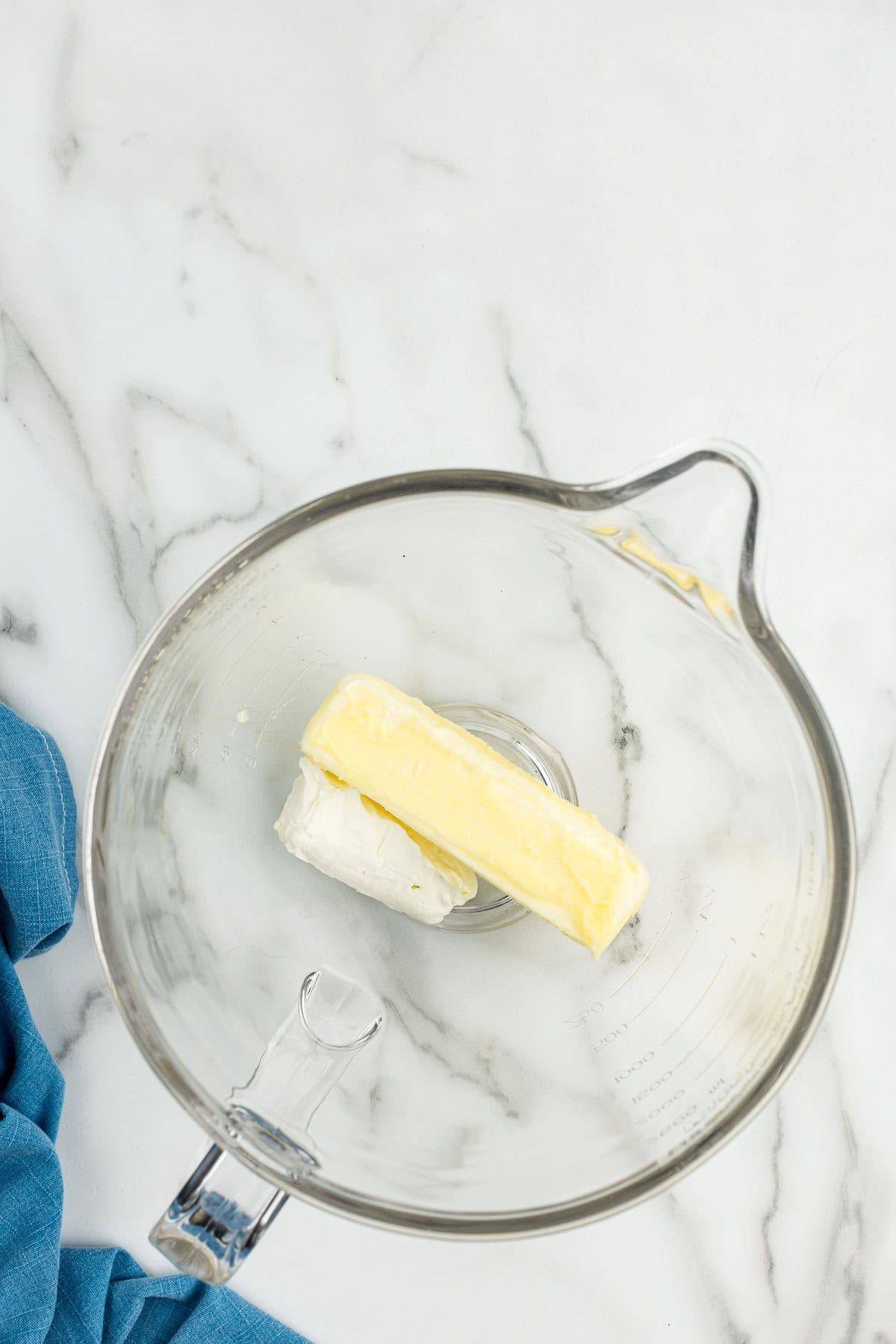 A measuring glass with butter and cream cheese in it.