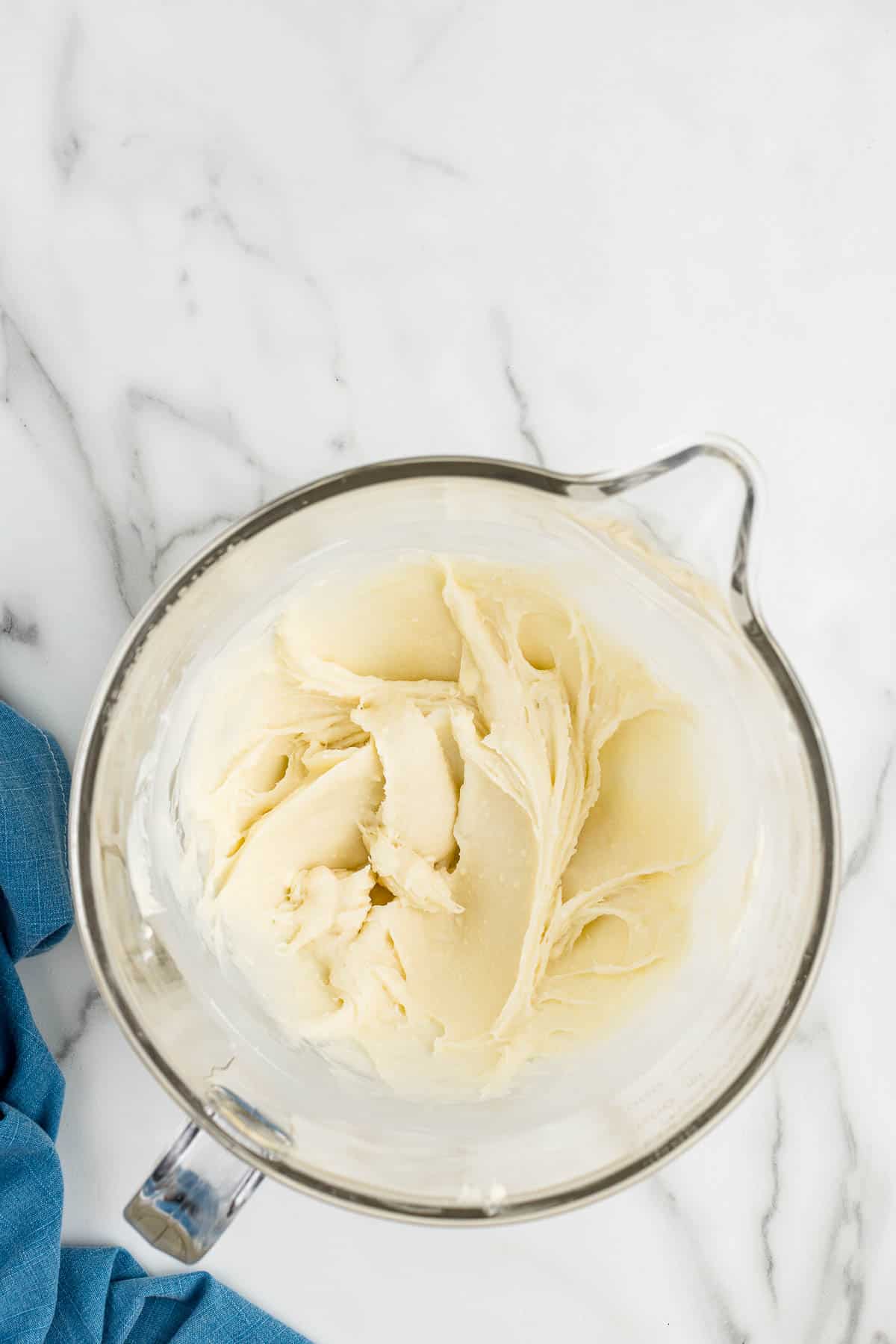 Blended frosting in a glass measuring cup.