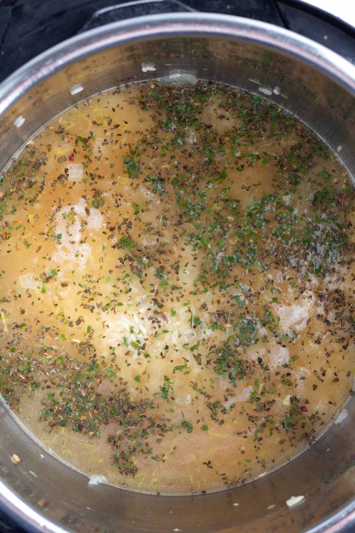 A pot of uncooked rice floating in seasoning and juices.