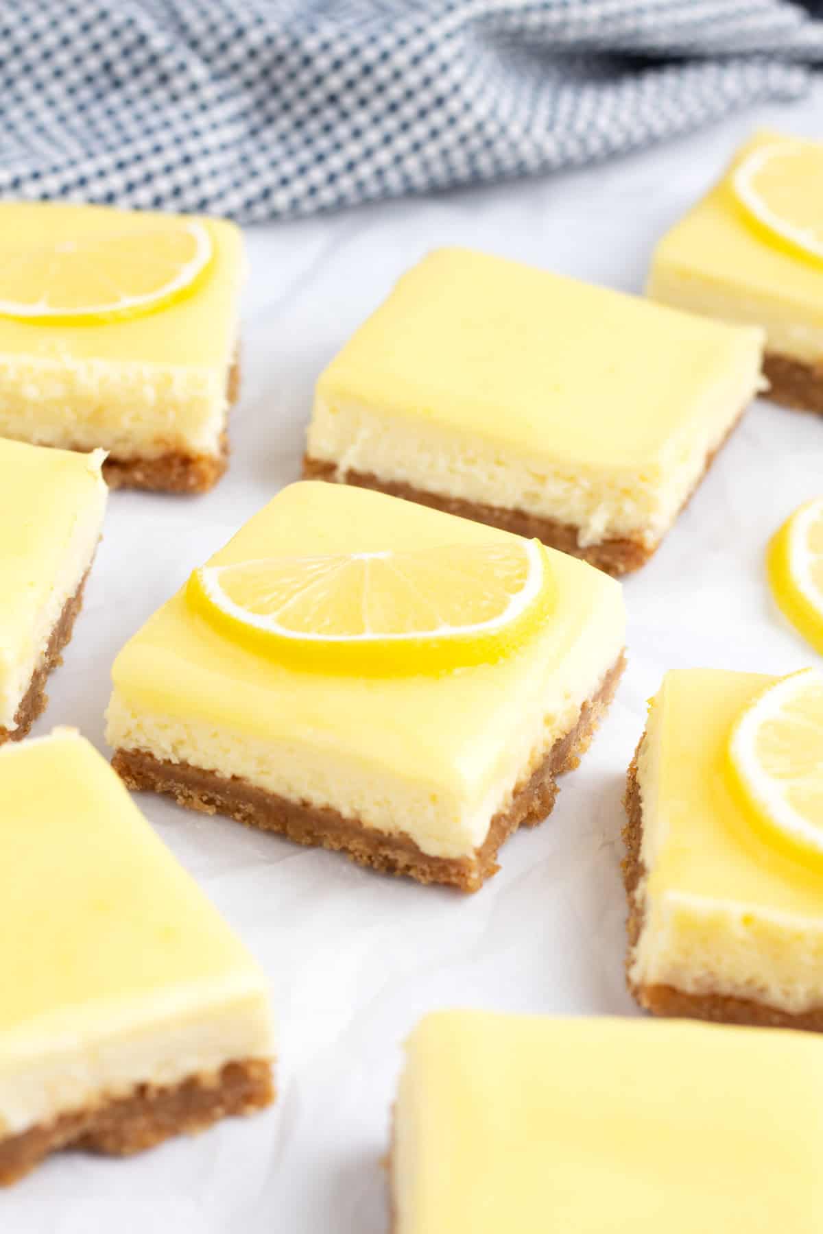 A cluster of cheesecake lemon squares on a piece of parchment paper.