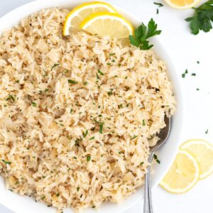 A large serving dish of lemon rice with a spoon in it.