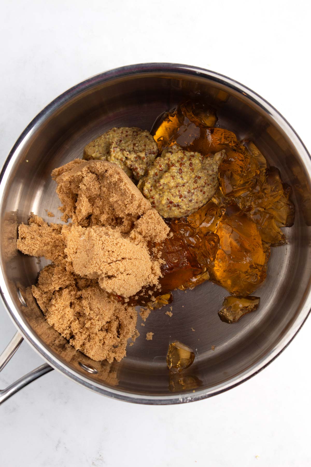 A pan with sugar, jelly, and mustard sitting unmixed.
