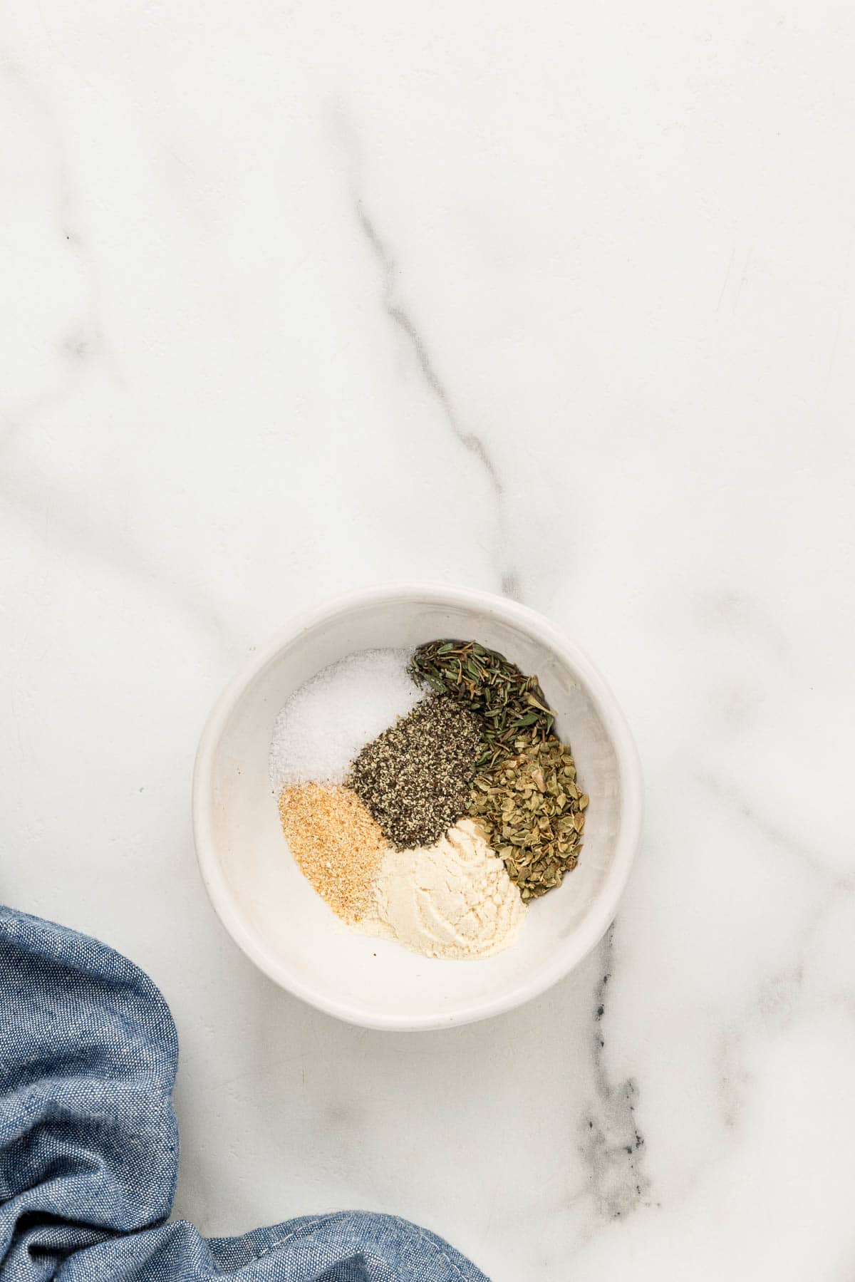 A small bowl of seasoning ingredients on a marble counter.