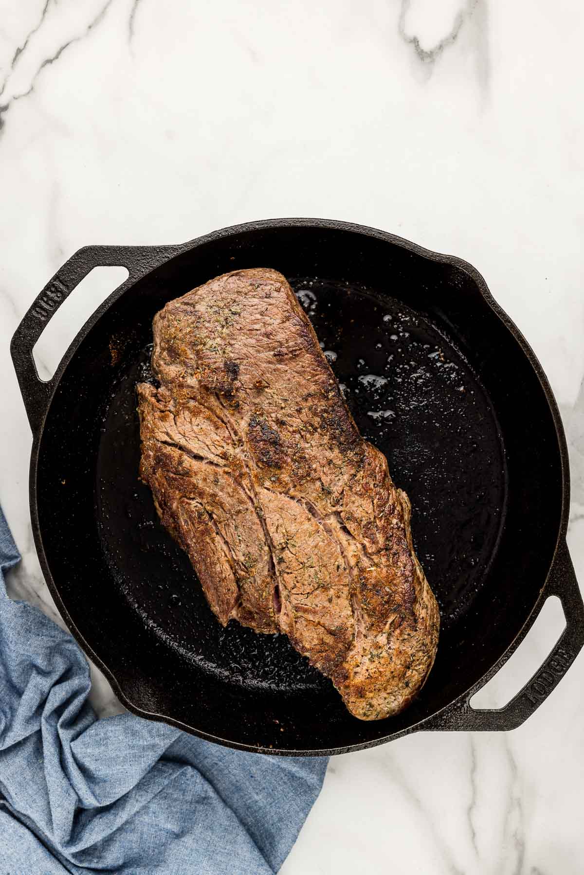 A large piece of meat in a cast iron skillet.