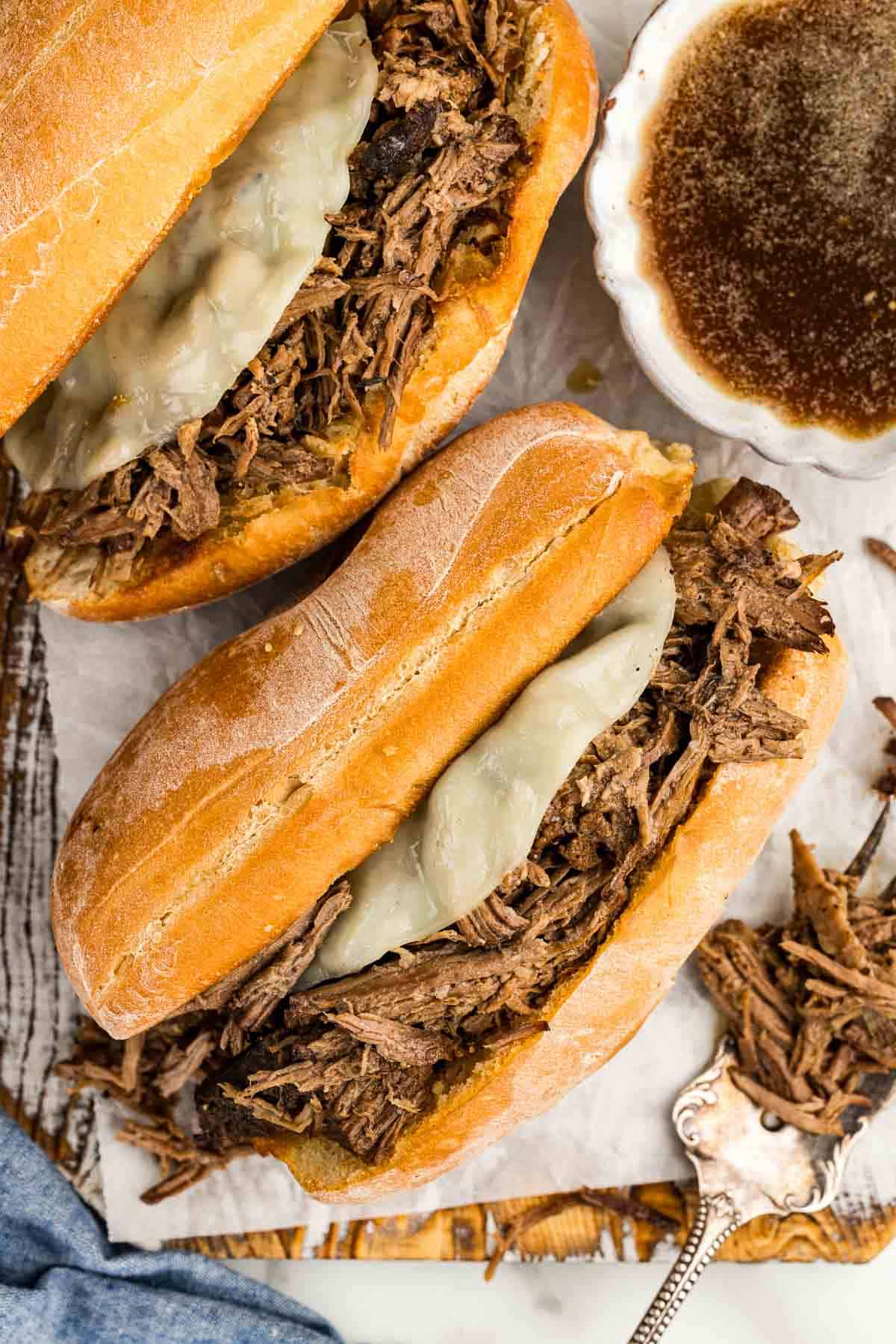 Two delicious meat sandwiches next to a bowl of French dip.