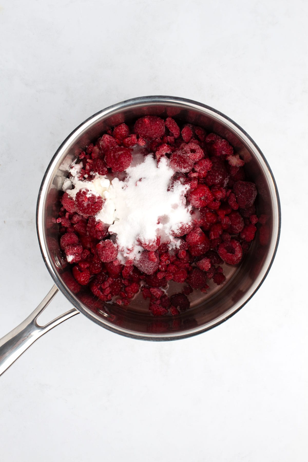 A pan with raspberry sauce ingredients in it.
