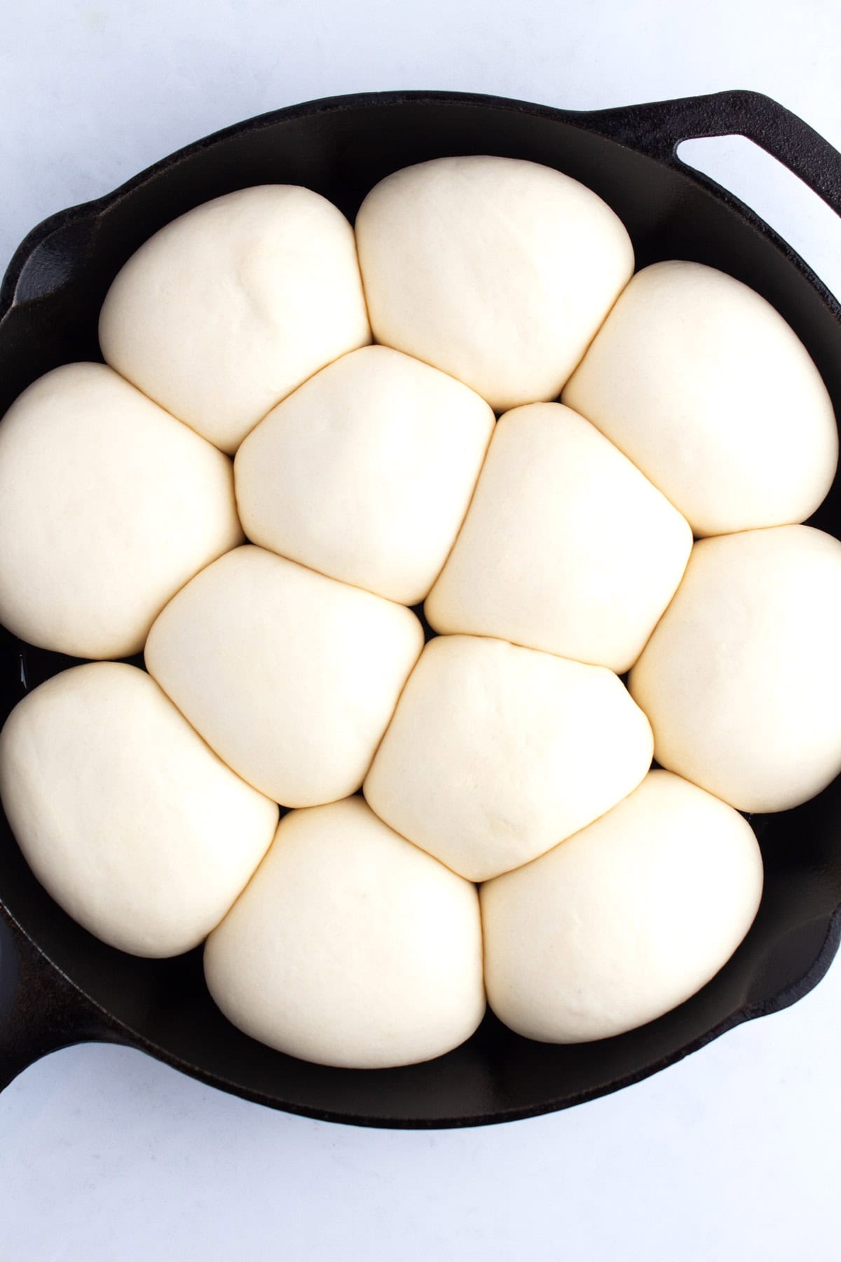 Expanded rolls of dough in a cast iron pan.