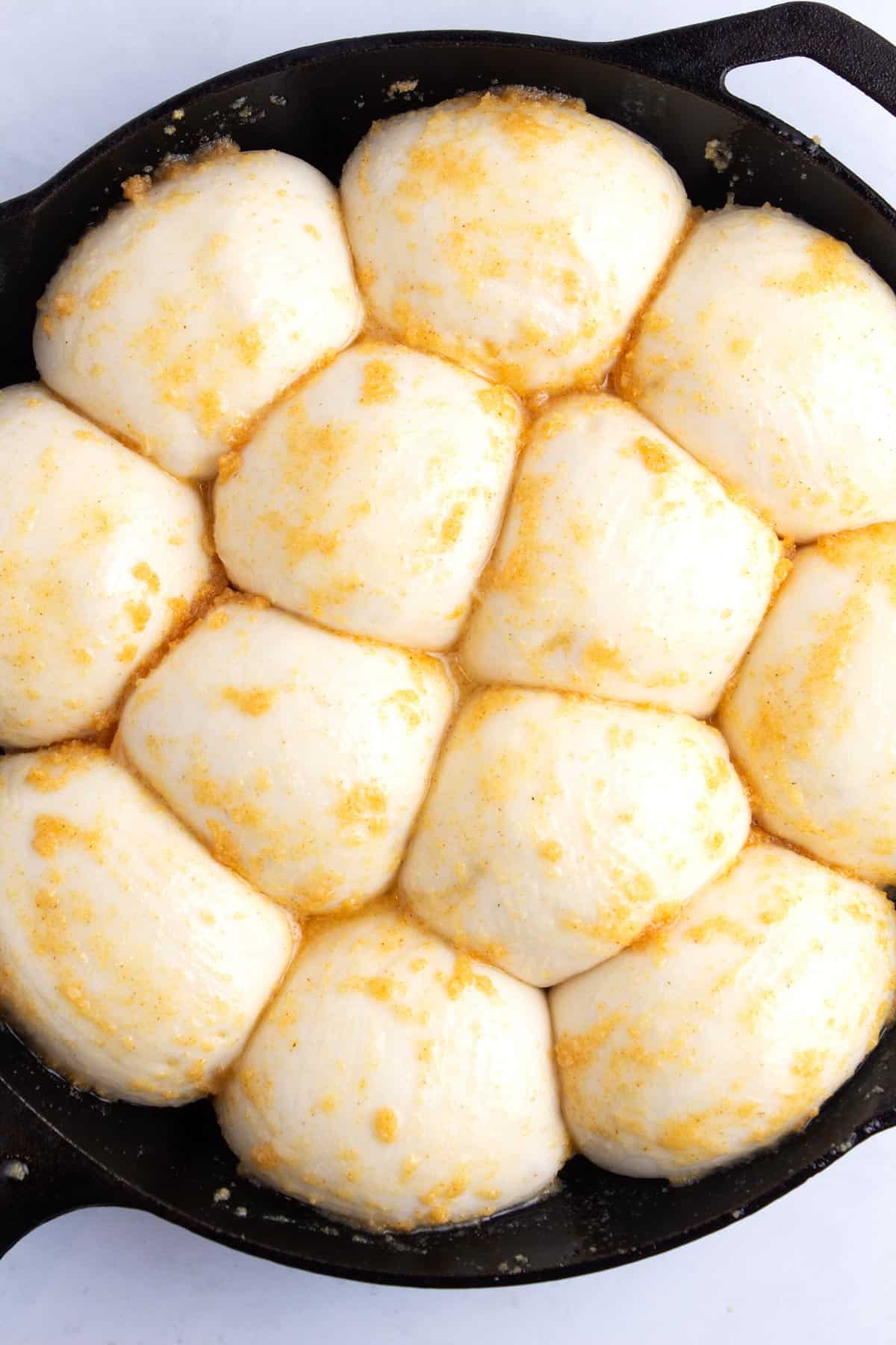 Fluffy balls of dough in a skillet topped with garlic and butter mixture.